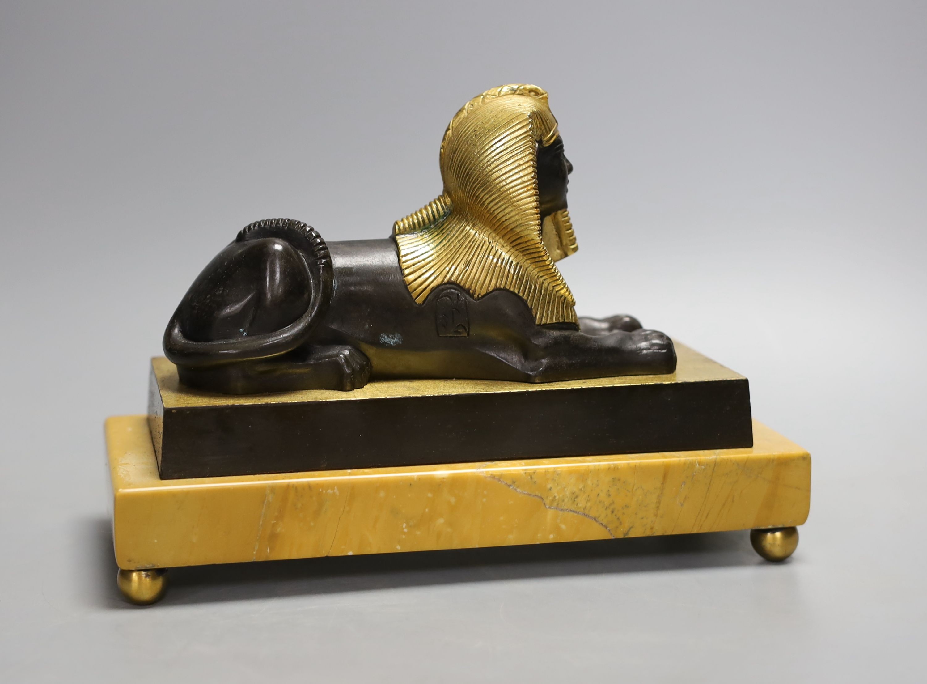 A parcel gilt bronze model of a sphinx on a Siena marble base - 22cm long